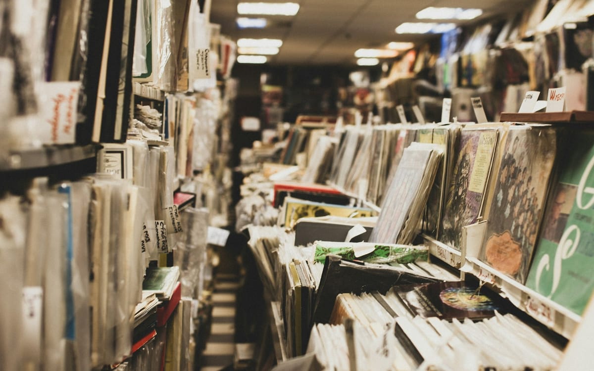 albums on shelves and on display in a record store - but in obvious disarray