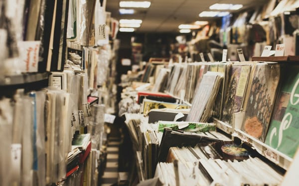 albums on shelves and on display in a record store - but in obvious disarray